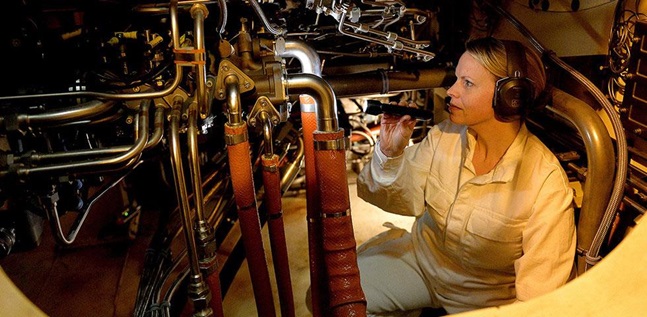 Female Marine Engineer Officer checking machinery with a torch