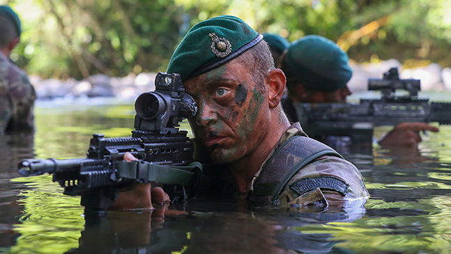 Royal Marines Commando in water pointing a gun