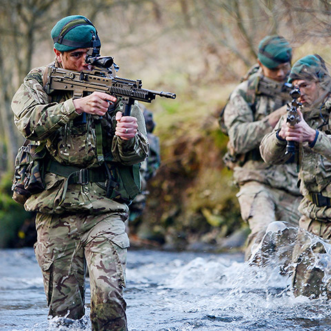 Royal Marines walking through water holding weapons