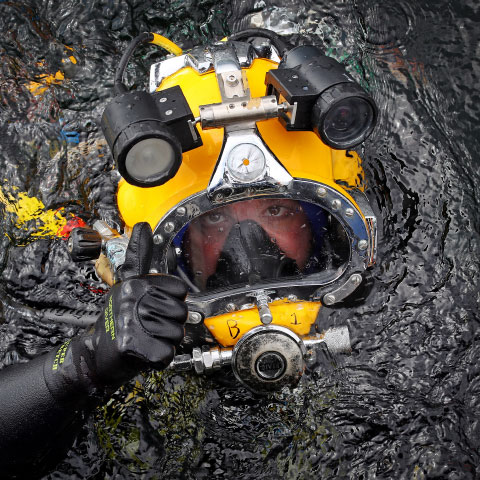 diver in water in yellow headgear photographed from above as they break the surface