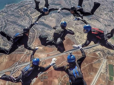 skydivers linked up in circle as they fall to dried fields below