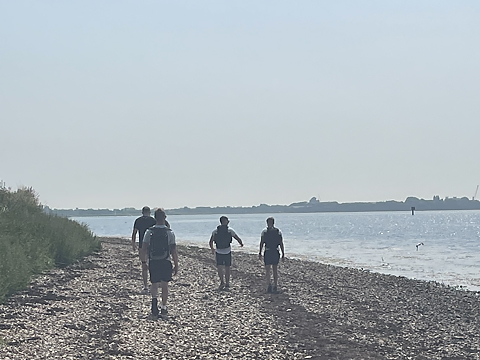 group of walkers walking away from camera on a coastal beach route on a sunny and bright day