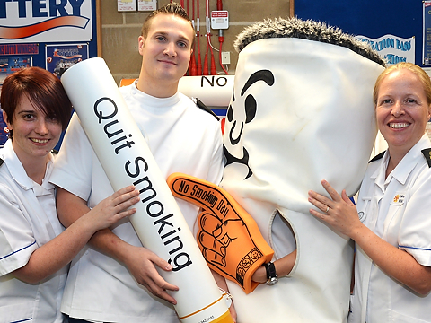 group of personnel with stubbed out cigarette mascot and quit smoking prop