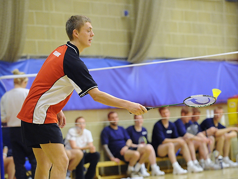 badminton player serving or returning with group in background