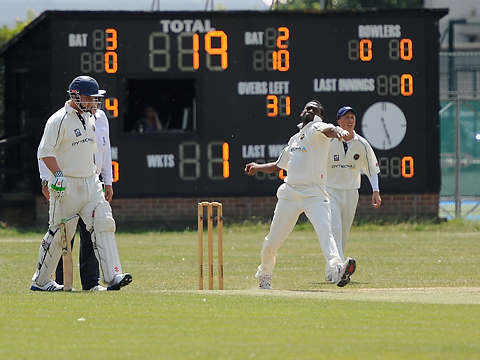 right handed seamer at crease about to bowl with scoreboard in background