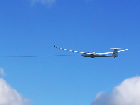 glider heading away on tow rope with blue sky backdrop