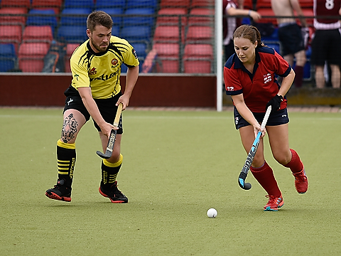 female naval hockey player in red taking on male counterpart in yellow