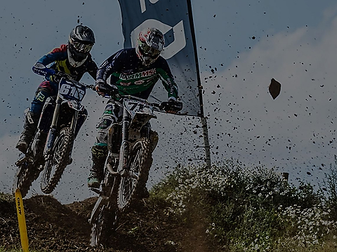 two motocross racers challenging for position on downward muddy slope