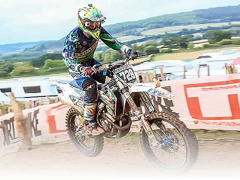 motocross racer accelerating on uphill section with countryside backdrop