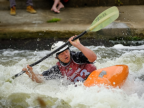 royal navy instructor in orange canoe with yellow paddle navigating white water course 