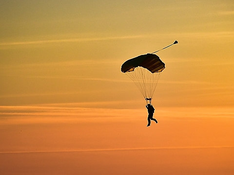 rn parachutist in silhouette against stunning orange sunset sky