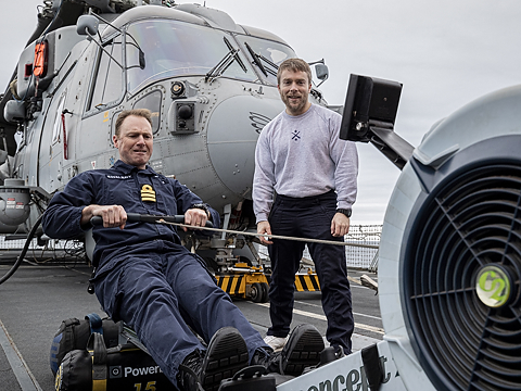 royal navy personnel using rowing machine on deck by helicopter