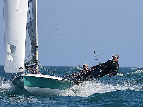 royal navy double hander in race, with sailor leaning to counter balance