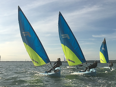 three racing single handers with blue and neon yellow sails