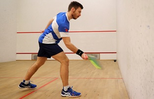 royal navy squash player warming up with forehand against side wall
