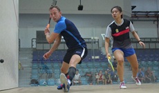 Royal Navy's Lieutenant Commander Matt Ellicott readying backhand with malaysian kit-dressed female opponent looking on to the right