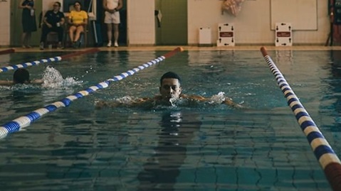 male swimmer doing breaststroke in swimming pool in lane
