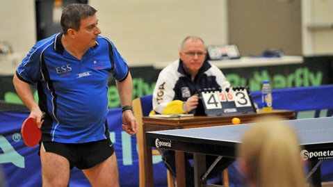 blue dressed navy table tennis player readying a forehand shot
