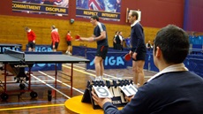 image taken behind scorer watching navy table tennis players in competition