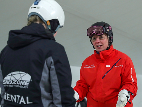 ski instructor dressed in red giving training to participant in blue