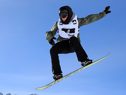 snowboarder jumping across clear blue sky