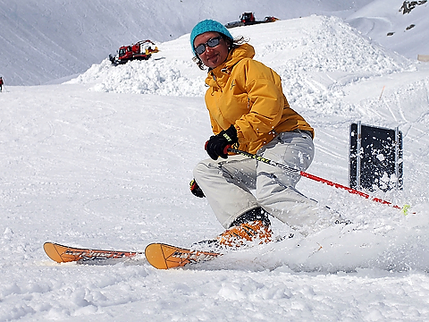 yellow jacketed skier sliding parallel to a stop