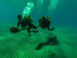 xdg divers in scuba gear analysing sea bed