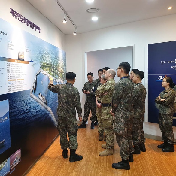 Officers from the Royal Navy and Korean Navy in front of a briefing board