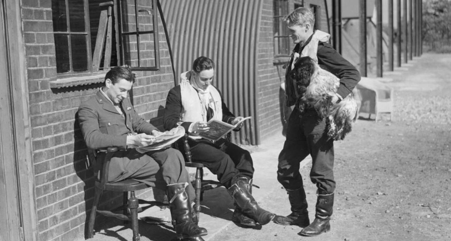 Relaxing between sorties outside their crew room at RAF Fowlmere in Cambridgeshire are, from left, Pilot Officer Wallace âJockâ Cunningham, Sub Lt Arthur Giles Blake and New Zealander Flying Officer Frank Brinsden (holding Rangy the spaniel). Blake â known by comrades as âAdmiralâ â was one of 23 Naval aviators seconded to the RAF in 1940. The 23-year-old had been serving at HMS Daedalus when he was drafted to 19 Sqn. He is one of only around half a dozen credited Naval â during WW2 status granted to pilots who downed five or more enemy aircraft.