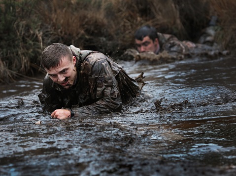 A trainee Royal Marines Officer Cadet struggles through the water on a gruelling assault course