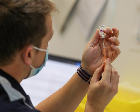 Surgeon Lieutenant Ryan Dodd fills a syringe with the vaccine
