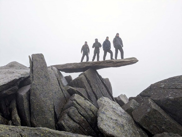 The team move cautious down a rocky slope in low cloud