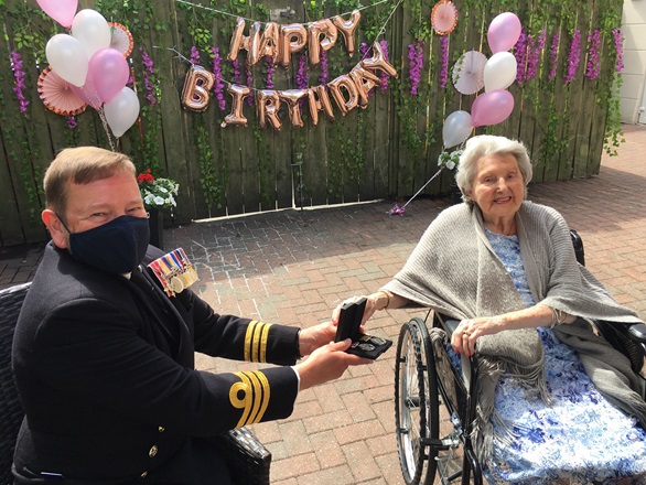 Commander Andy Swain presents Jacqueline with her medals on her 100th birthday