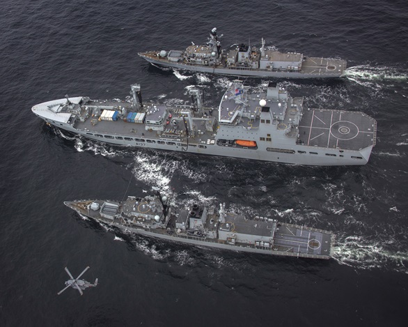 RFA Tiderace conducts a double replenishment at sea with HMS Lancaster (bottom) and Westminster (top) as a Canadian Sikorsky helicopter flies past