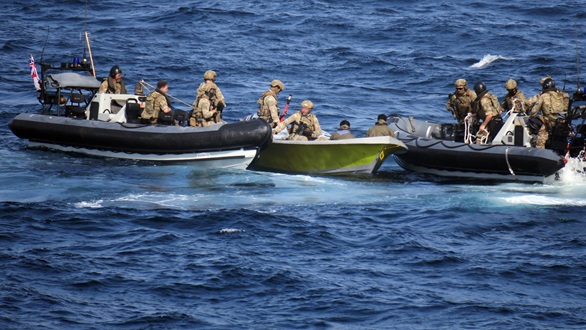 Two of Lancaster's sea boats flank the suspect skiff as Royal Marines retrieve the weapons cache