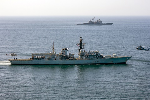 Omani and US Navy helicopters work with HMS Montrose with American cruiser USS Port Royal in the background