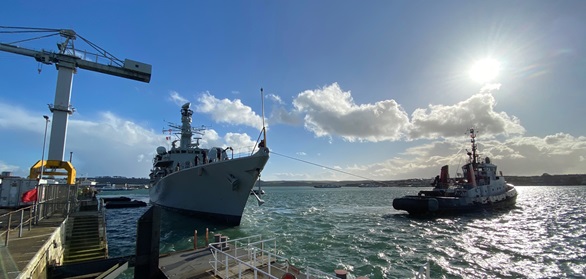 A tug helps HMS Portland away from the jetty