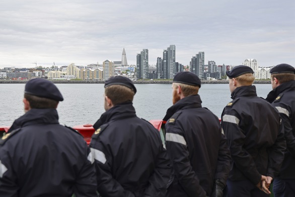 Sailors on Protector's upper deck admire the Reykjavik skyline as the ship enters harbour