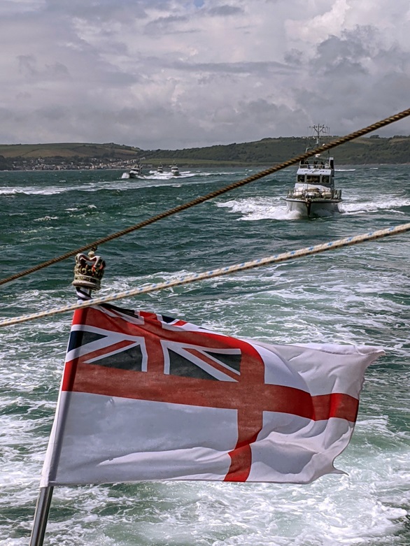 HMS Charger's White Ensign billows as HMS Smiter leads a line formation of P2000s